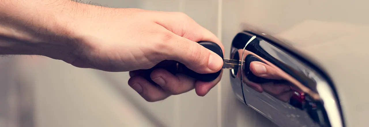 Hand turning a car key in the door lock