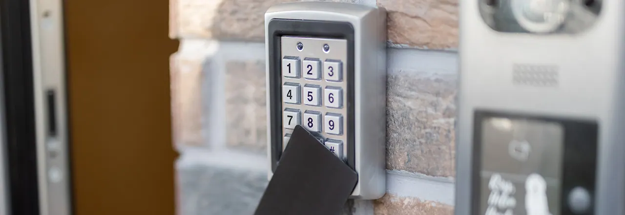 Card held to a keypad entry reader on a brick wall