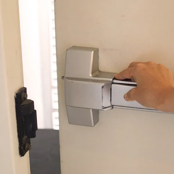 Hand pressing a panic bar exit device